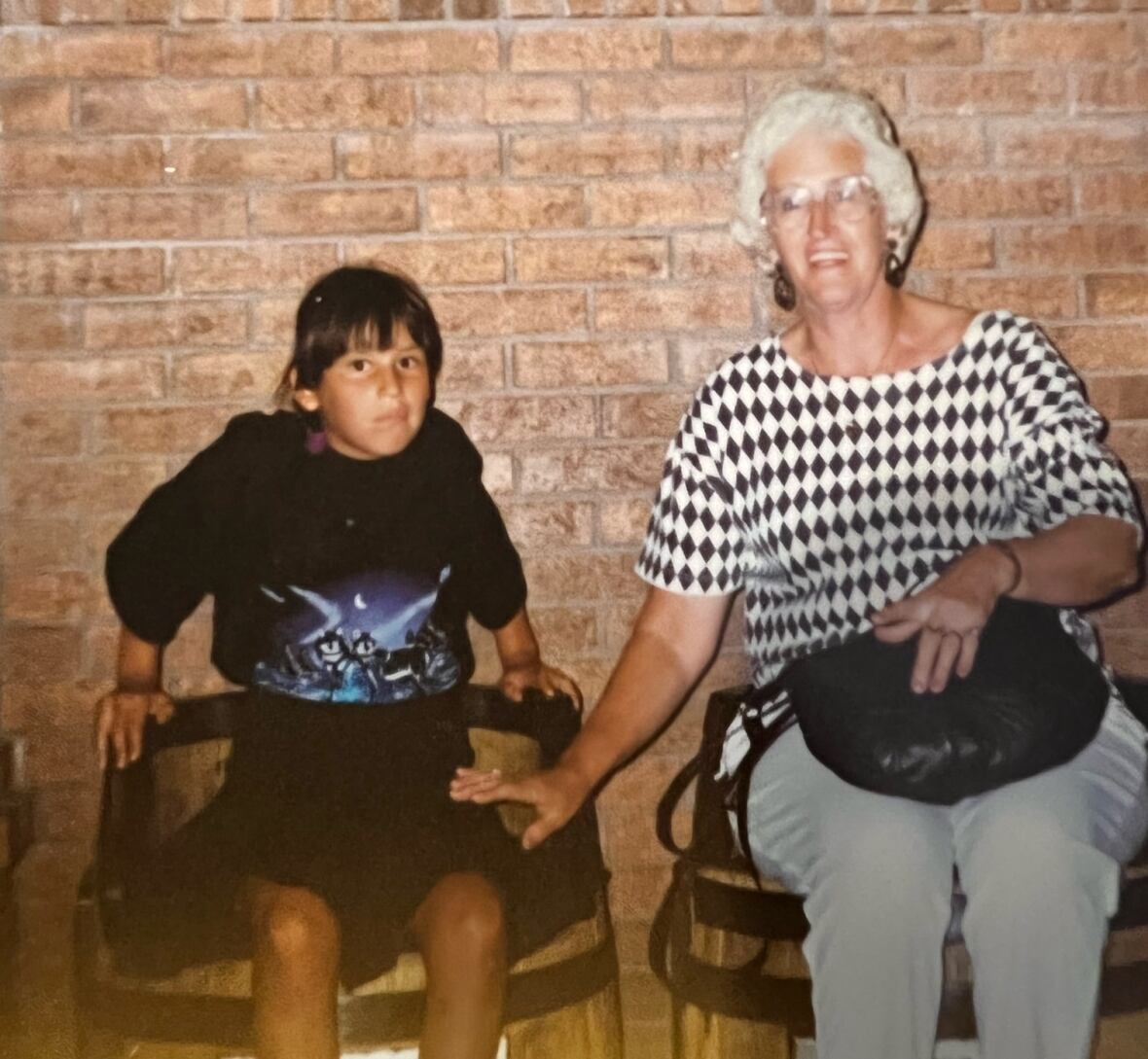 A girl sits in a chair next to a woman.