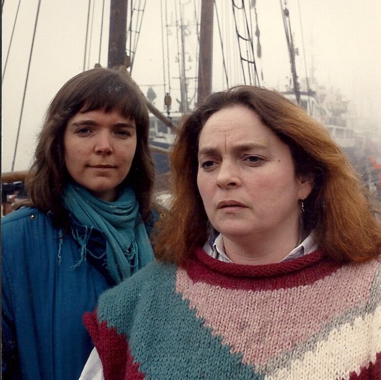 Two women stand on a ship.