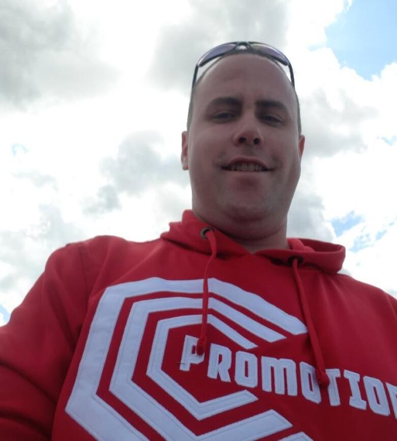 Photo shot from below of a man in sunglasses and red hoodie