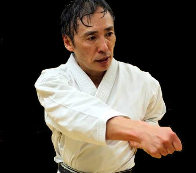 A sweating Japanese man in a karate uniform in a fighting pose.