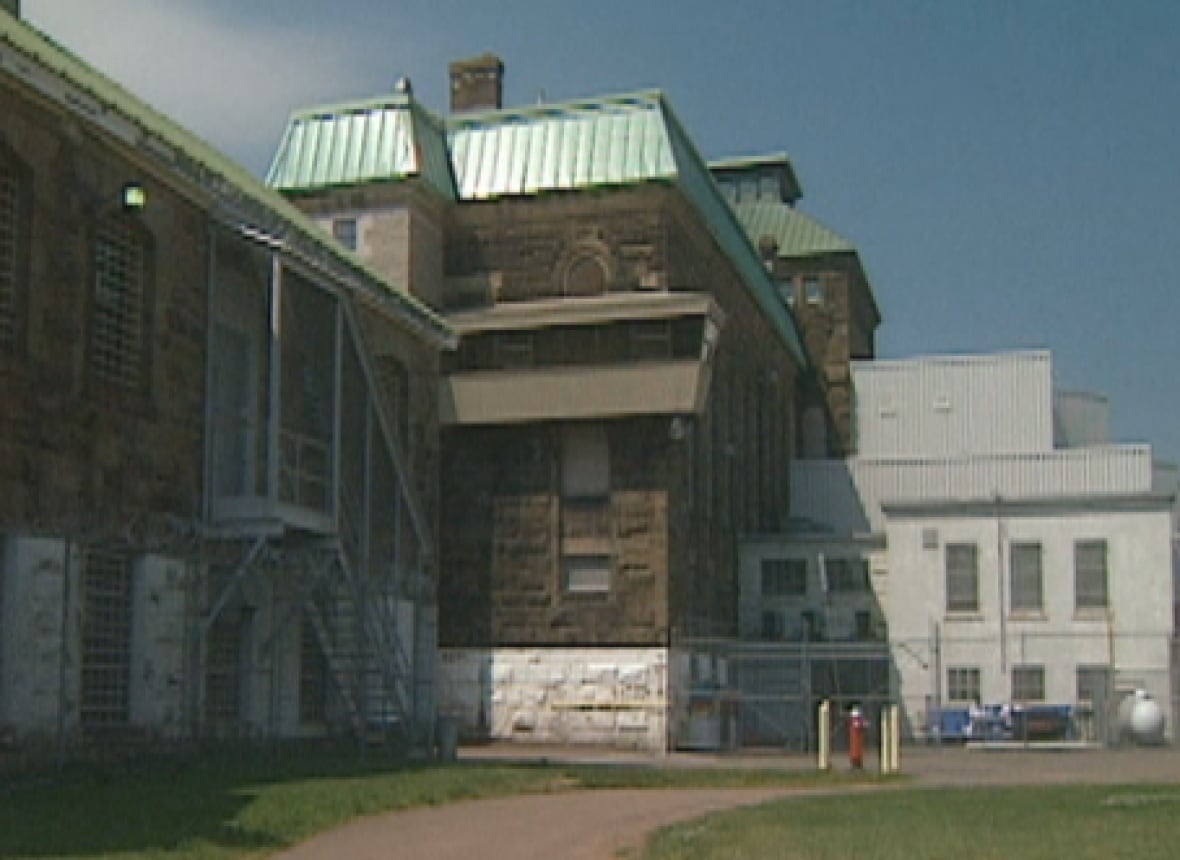 A large old grey stone building with a green metal roof.