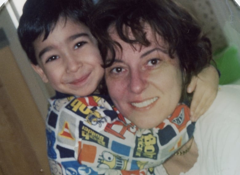 A young boy wearing a Bob the Builder shirt tightly hugs his mother, who is smiling.