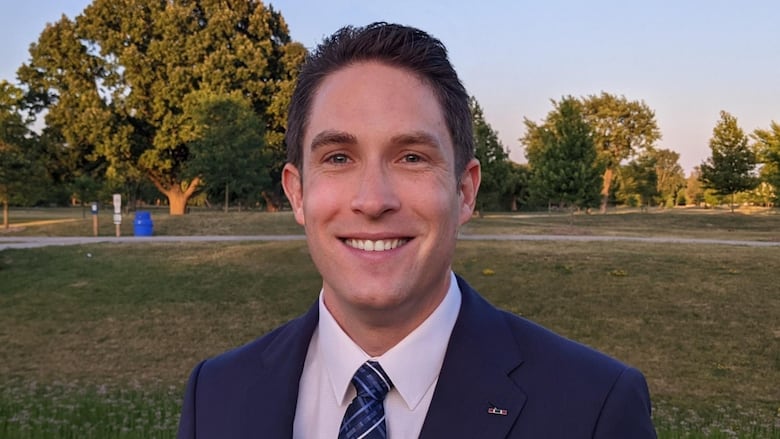 James Dorner in a suit in a park.