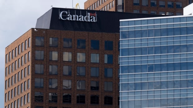 Government office buildings, like these in Gatineau, Que., are filling back up with federal workers including 35,000 new hires. The public service grew by 12 per cent during the two-year COVID-19 pandemic, adding billions to Ottawa's payroll. A federal government logo on a high-rise.