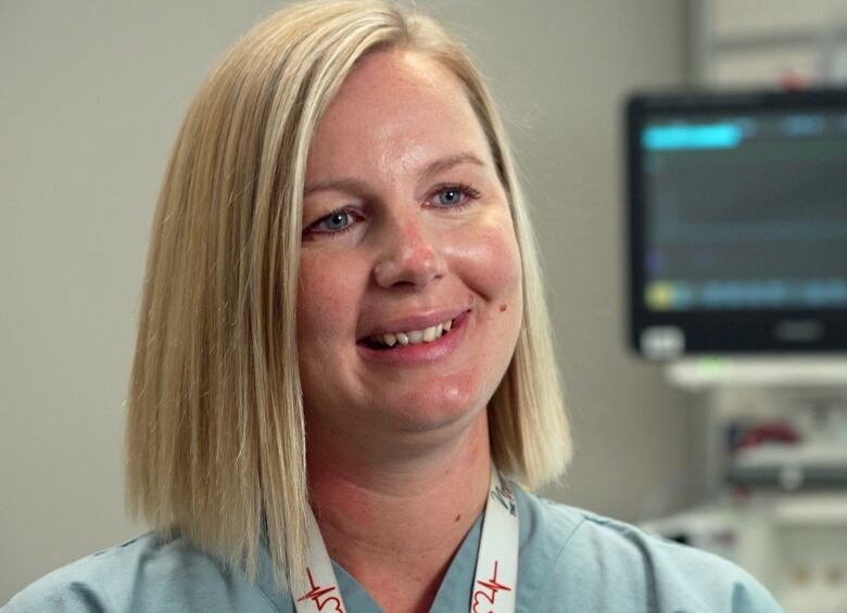 A smiling blonde woman wearing scrubs.