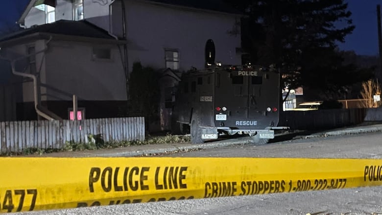 A police tactical truck at the fence of a house.