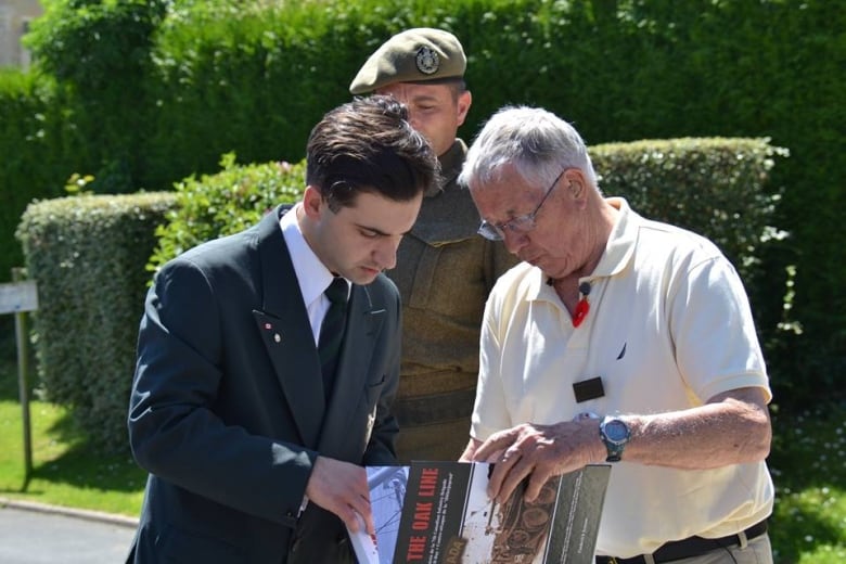 Deux hommes regardent un livre qu'ils tiennent.