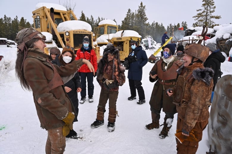 A group of actors laugh together in the snow on the set of the film Polaris.