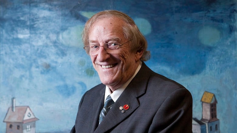 An older man smiles and looks into the camera.