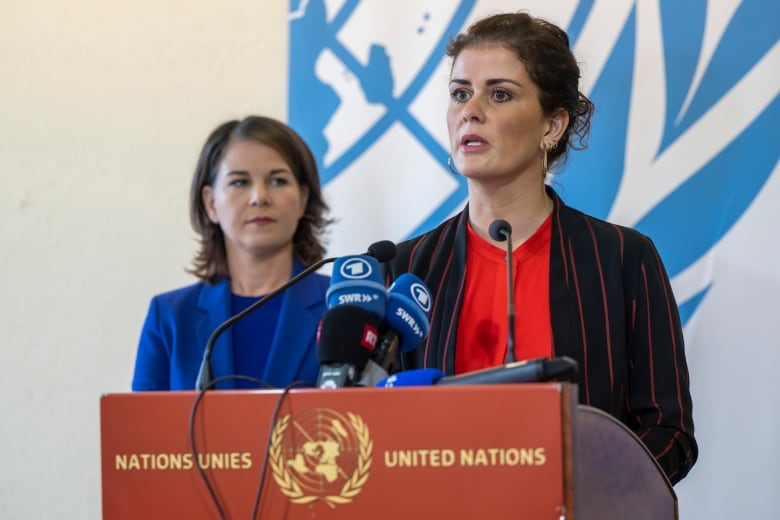 Two dark-haired women are speaking from a podium labeled 