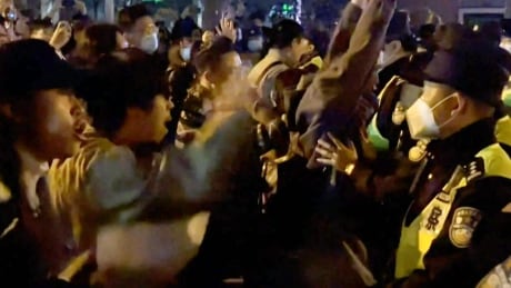 This frame grab from eyewitness video footage made available via AFPTV on November 27, 2022 shows demonstrators shouting slogans as police hold their positions, in Shanghai. - Angry crowds took to the streets in Shanghai in the early hours of November 27 and videos on social media showed protests in other cities across China, as public opposition to the government's hardline zero-Covid policy mounts. (Photo by AFPTV / AFP) (Photo by -/AFPTV/AFP via Getty Images) 1245133930
