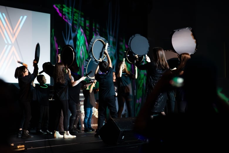 A group of children holding drums above their heads. 