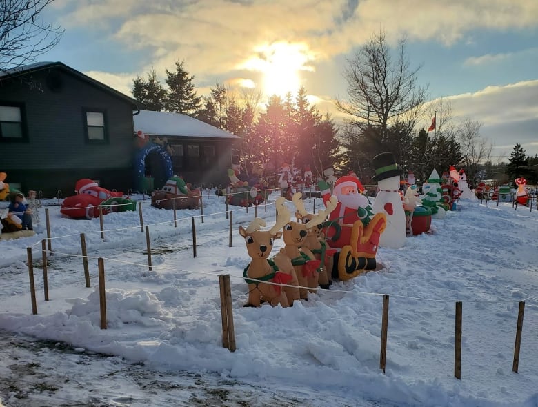 A bunch of inflatable Christmas decorations are displayed on a front lawn.