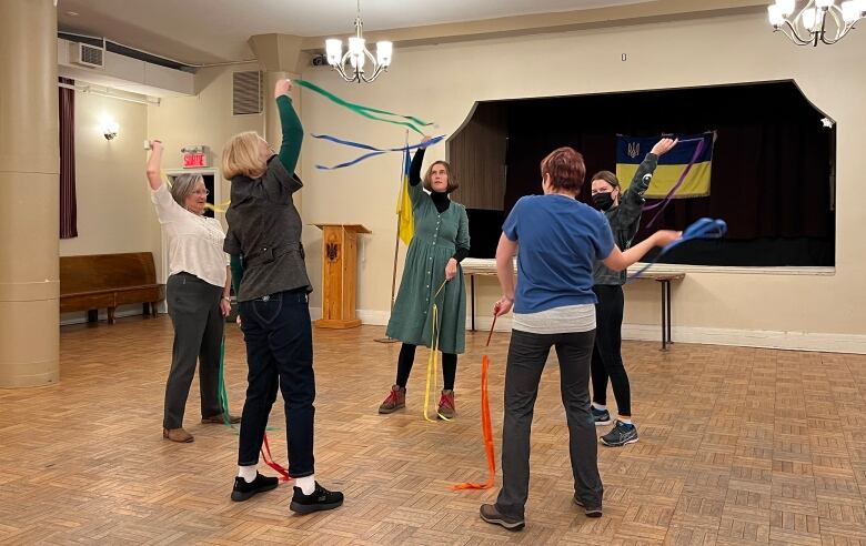 Wide view dancers in a circle, holding ribbons