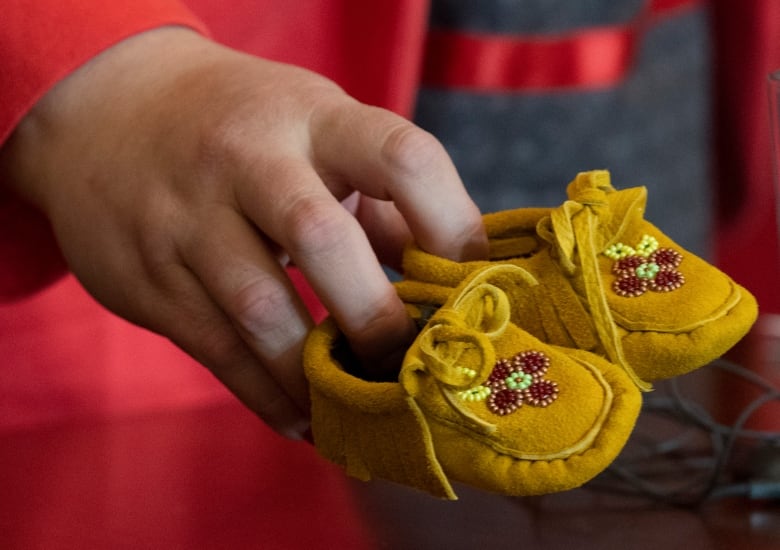 Une paire de mocassins pour enfants représente les dizaines de milliers d'enfants des Premières Nations qui sont retirés de force de leur foyer, de leur communauté et de leur famille.