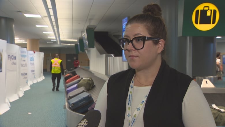 A yvr spokesperson stands near white walls hiding 2,500 lost bags.