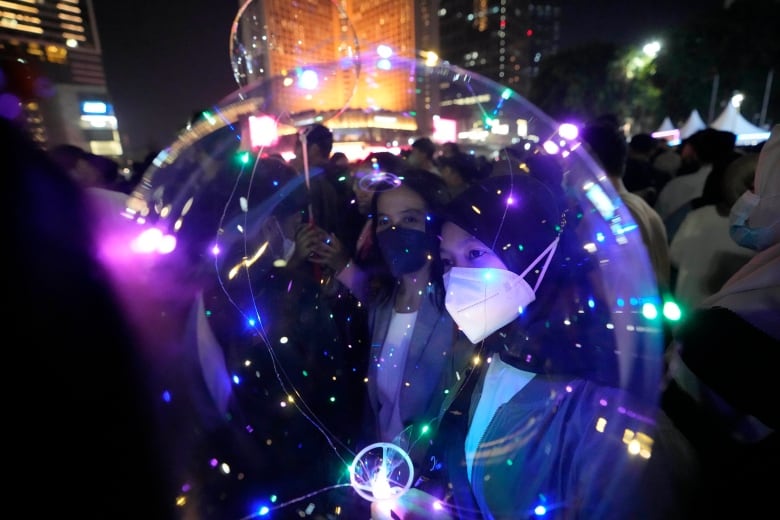 People in face masks gather in Jakarta behind a huge bubble.