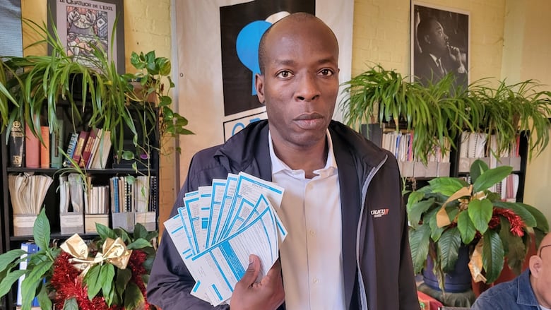 Man stands while holding several fines.