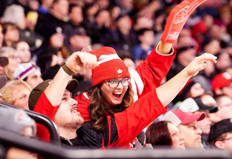 A man and a woman wearing red jerseys in a cheering crowd