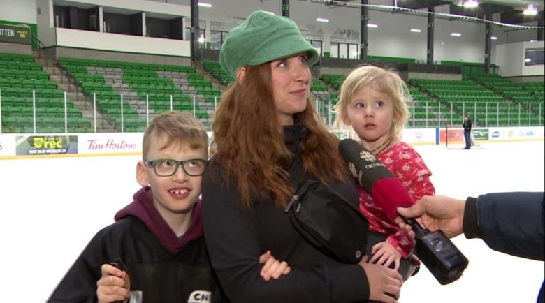 A woman and a boy and girl speak into a CBC microphone.