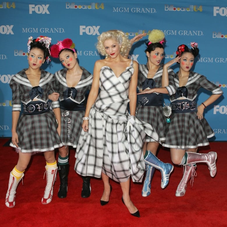 Five women stand on a red carpet. 