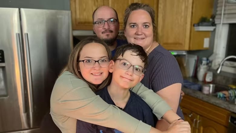 Un hombre y una mujer mirando con las gafas puestas, un niño y una niña, parados en la cocina.