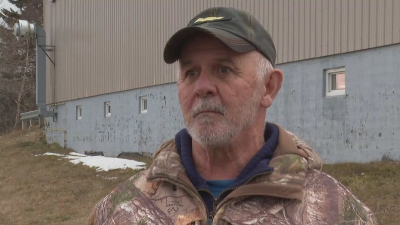 Man in ball cap and camoflauge-coloured jacket.