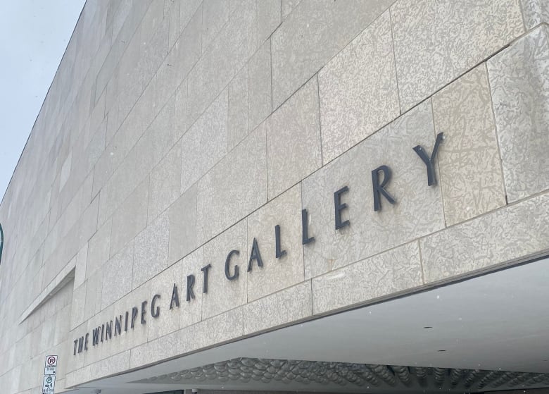 The exterior of a building is seen, with the name Winnipeg Art Gallery on it.