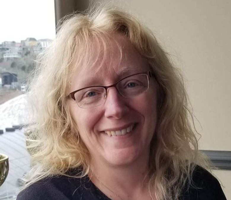 A woman wearing glasses smiles.