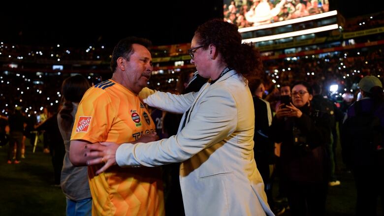 Carmelina Moscato, right, coach of Tigres UANL femenil, talks to and embraces the father of a player.