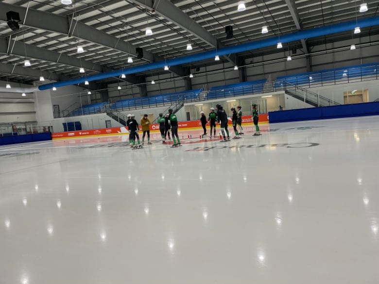 Short track speed skaters on the ice in a large arena. 