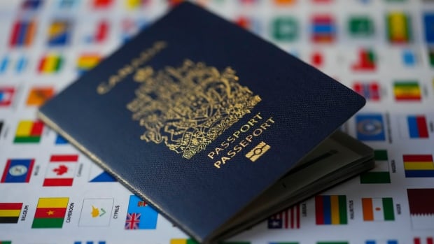 A Canadian passport sits on a poster featuring flags of the world