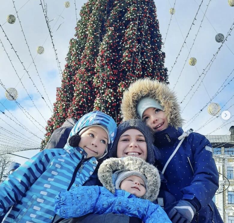 Woman and three children around Christmas tree outdoors