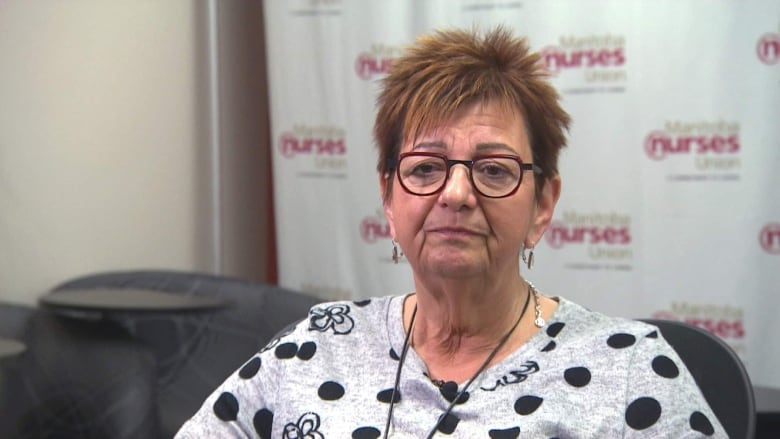 A woman wears maroon-coloured glasses, a polka-dot shirt and has spiked red hair.