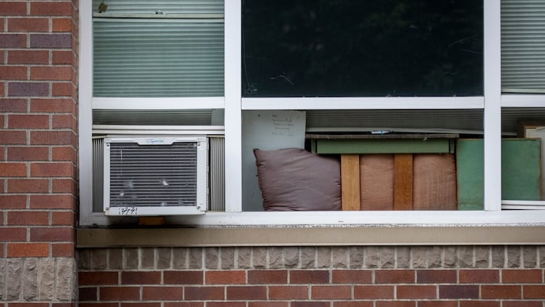 An air conditioner sits on the side of a window of an apartment.
