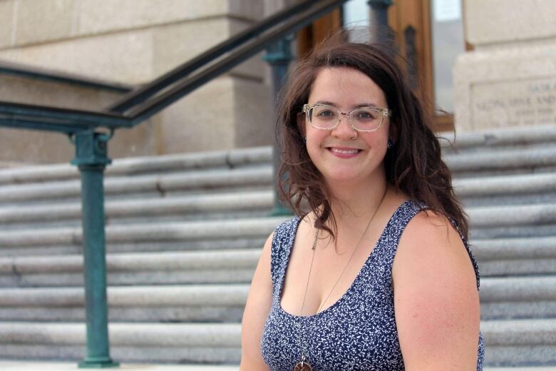 A woman in aa blue top sits at a staircase.