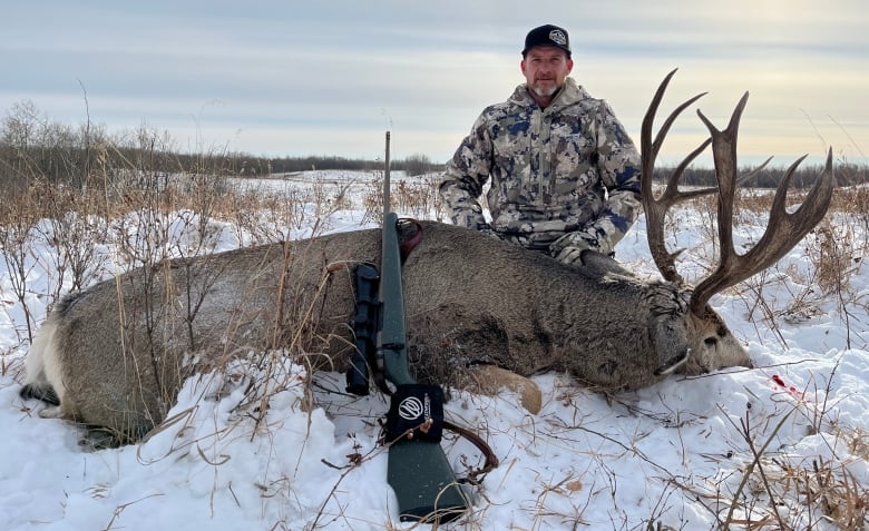 A man kneels next to a dead animal.