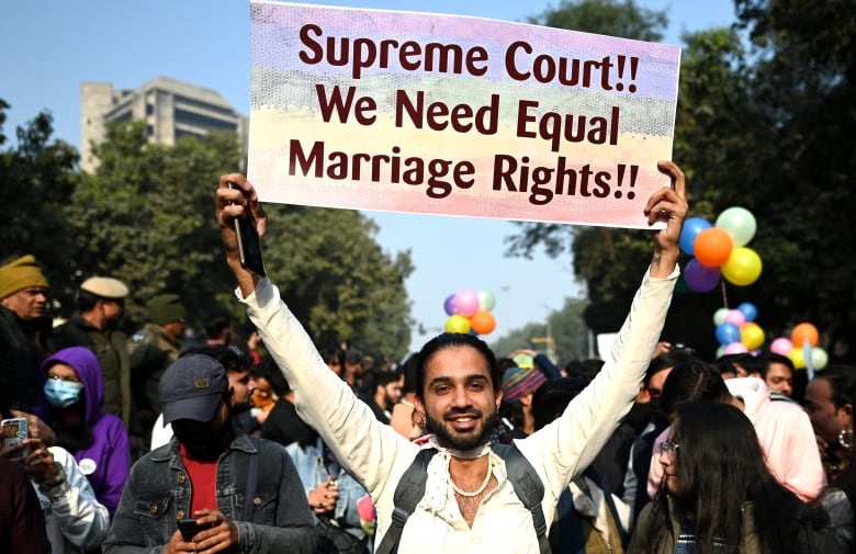 A man holds a sign over his head with the words 