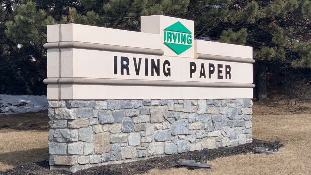 J.D. Irving Ltd. is New Brunswick's largest forestry company. It runs a pulp, paper and tissue mill in Saint John that will pay a combined $4.7 million in municipal and provincial property tax in 2023. That is down from $6.4 million it paid in 2012. A stone sign in front of some green trees with ettering on it that says Irving Paper.