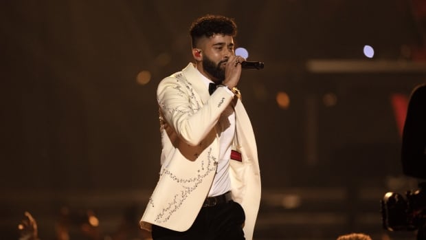 AP Dhillon performs at the 2023 Juno Awards in a white suit with silver gems. 