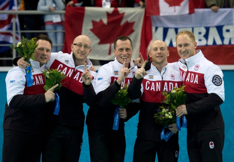 Five curlers celebrate winning the 2014 Olympic curling gold medal.