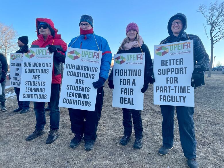 People standing outdoors, holding signs.