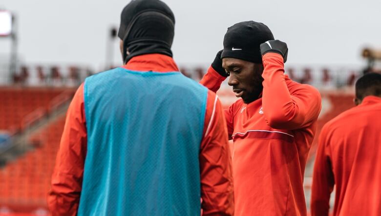 A men's player puts on a hat during a training session.