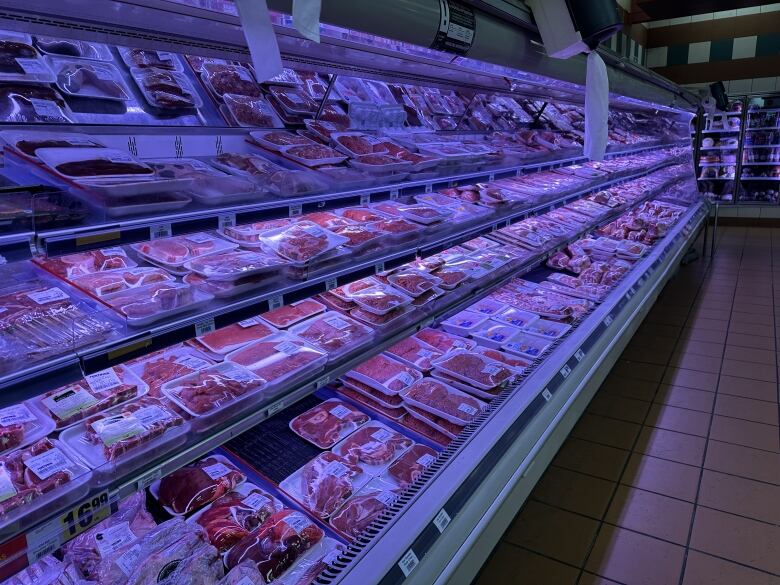 Meat aisle in a grocery store showing all products packaged using plastic wrap and thermal labels. 