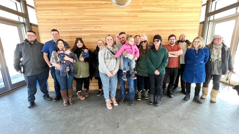A group of over a dozen people pose for a photo in a warming shack at a park.