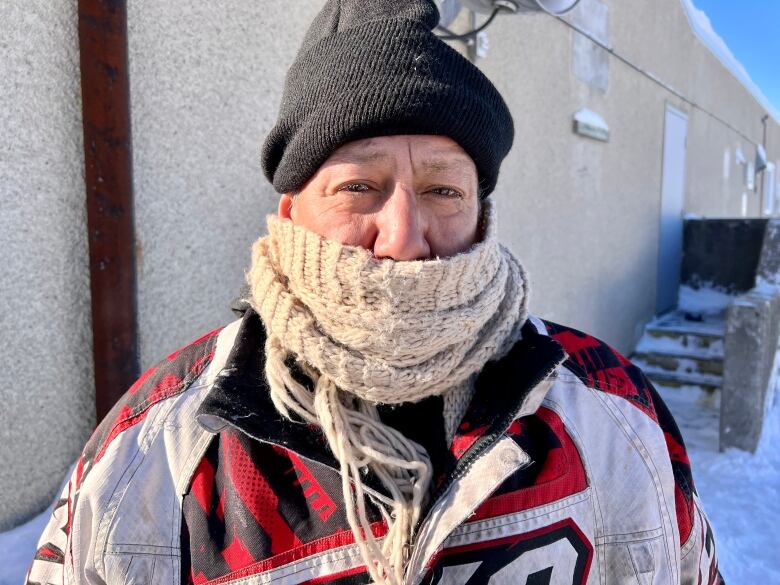 A man outside wearing a scarf around his face