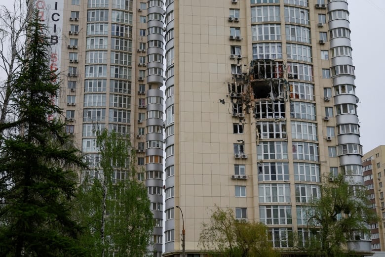 Two large windows of a highrise apartment building are seen shattered and blackened. 