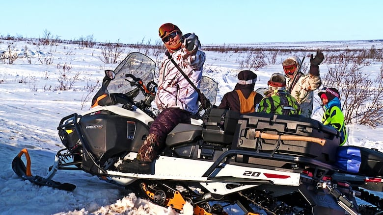 Five people pile onto a snowmobile with a bunch of gear.