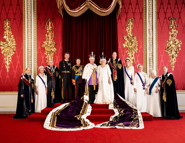 Several people stand beside two people wearing crowns.