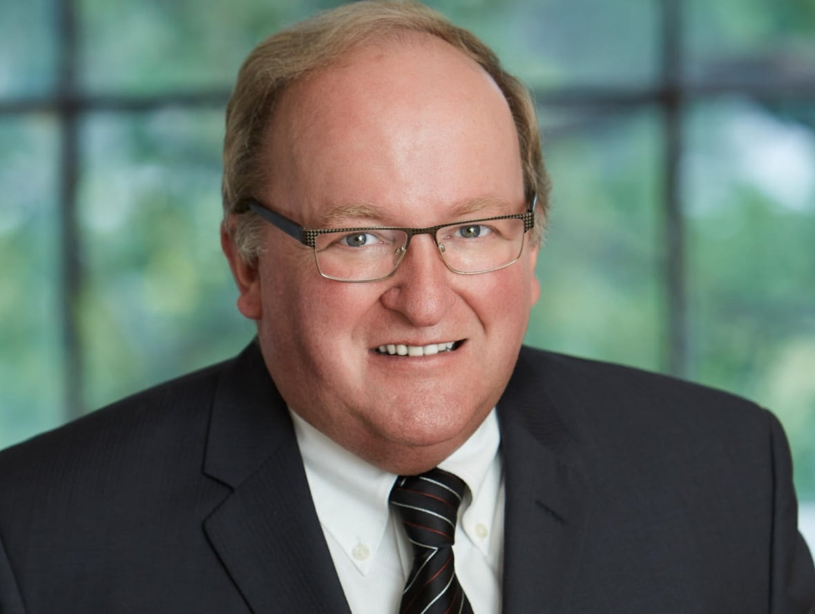 A man in a suit with a blurred background.
